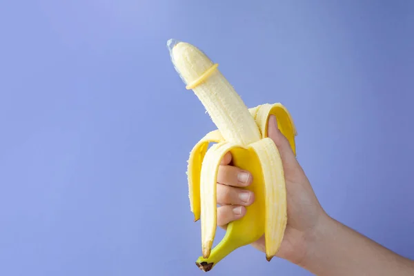 ライトブルーの背景 クローズアップ テキストのためのスペースにコンドームでバナナを保持する女性 安全なセックスの概念 — ストック写真