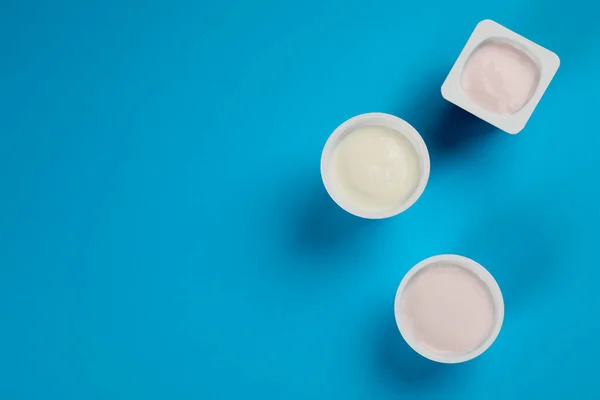 Bicchieri Plastica Con Gustoso Yogurt Sfondo Azzurro Posa Piatta Spazio — Foto Stock