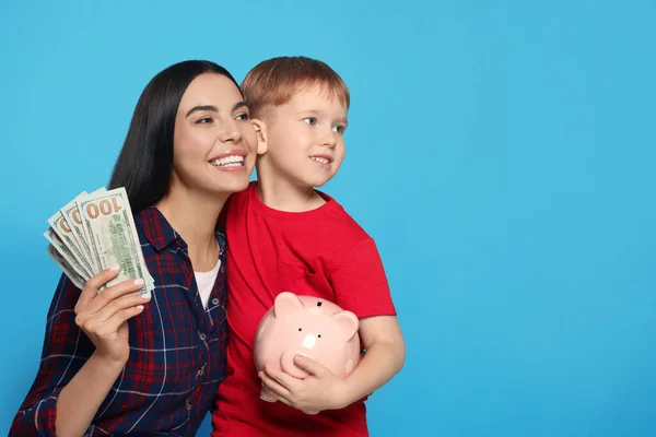 Moeder Met Geld Haar Zoon Met Spaarvarken Bank Lichtblauwe Achtergrond — Stockfoto