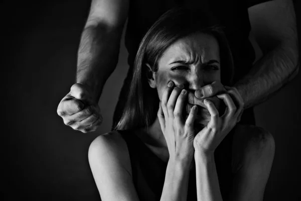 男人在黑色背景下虐待吓坏了的女人家庭暴力 — 图库照片