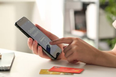 Beyaz ofis masasında internet bankacılığı uygulaması kullanan bir kadın.