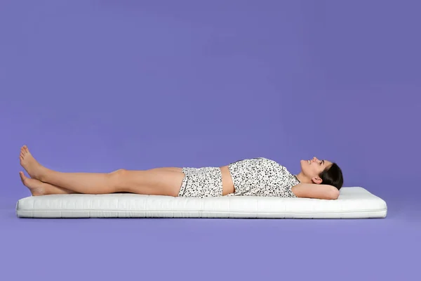 年轻女子躺在浅紫色背景的软垫上 — 图库照片
