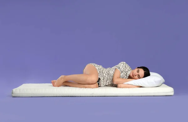 年轻女子躺在浅紫色背景的软垫上 — 图库照片
