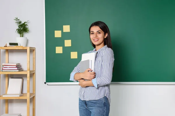 教室で黒板の本を持つ幸せな若い先生 テキストのスペース — ストック写真