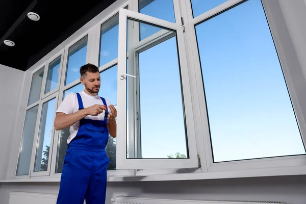 stock image Construction worker adjusting installed window with screwdriver indoors