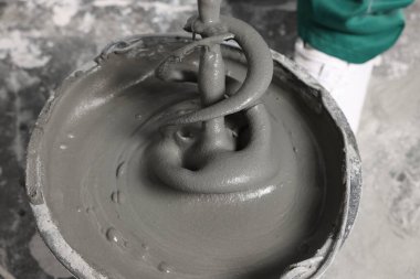 İçerideki kovaya beton karıştıran işçiler, yakın plan.