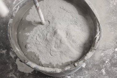 Kapalı alanda beton ve çimento tozu dolu kova, yakın plan.