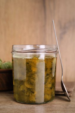 Bir kavanoz lezzetli bektaşi üzümü reçeli ve ahşap masada taze böğürtlenli kase.