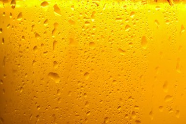 Glass of tasty cold beer with condensation drops as background, closeup