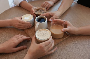 Friends drinking coffee at wooden table in cafe, closeup clipart