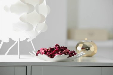 Tabakta aromatik potpuri, lamba ve yanan mum var. Odadaki beyaz çekmecelerin üzerinde.