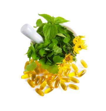 Taze yeşil otlu havan ve beyaz arka planda haplar.