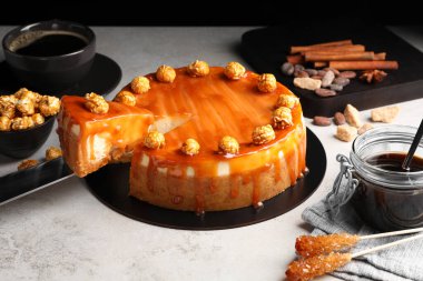 Taking piece of delicious caramel cheesecake with popcorn on light grey table