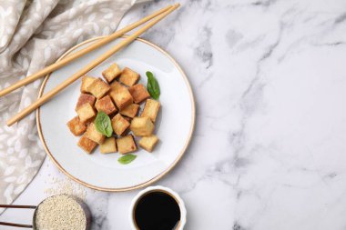 Beyaz mermer masada servis edilen fesleğenli leziz kızarmış tofu. Metin için boşluk