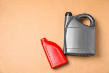 Açık kahverengi arka planda farklı kaplarda motor yağı, düz yerde. Metin için boşluk