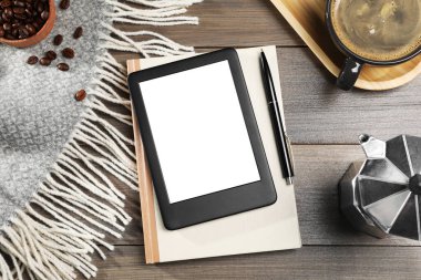 E-kitap okuyucusu, defter ve kahveyle tahta masada, düz yatıyordu. Metin için boşluk