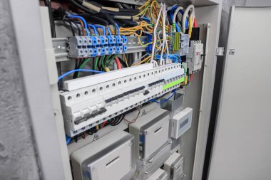 Elektrik sayaçları ve sigorta kutusunda bir sürü kablo olan panel