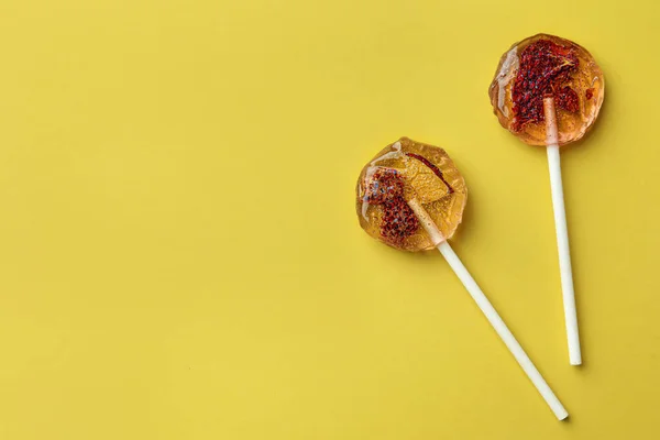 Stock image Sweet colorful lollipops with berries on yellow background, flat lay. Space for text