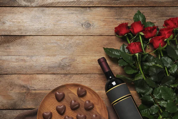 一壶红葡萄酒 美丽的玫瑰和心形巧克力糖果放在木制桌子上 平平的躺着 案文的篇幅 — 图库照片