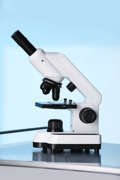 Moderne Microscoop Metalen Tafel Tegen Lichtblauwe Achtergrond — Stockfoto