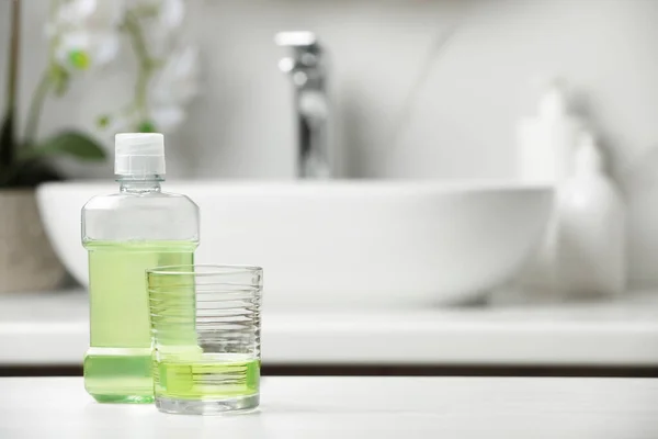 stock image Bottle and glass with mouthwash on white countertop. Space for text