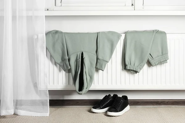 stock image Heating radiator with clothes and shoes in room