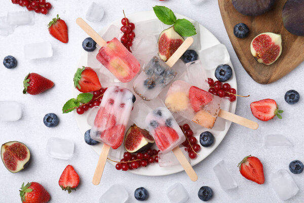 Flat lay composition with fruit and berry ice pops on white table