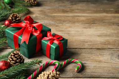 Hediye kutuları, şeker kamışları, köknar ağacı dalları ve ahşap masada Noel dekorasyonu, metin için yer