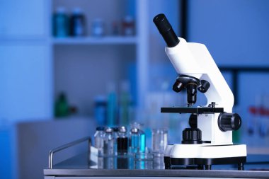 Modern medical microscope on metal table in laboratory, space for text