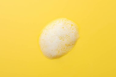 Sarı arka planda tüylü sabun köpüğü damlası, üst görünüm