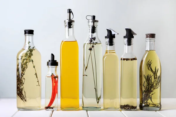 Flaschen Mit Verschiedenen Speiseölen Auf Weißem Holztisch Vor Hellem Hintergrund — Stockfoto