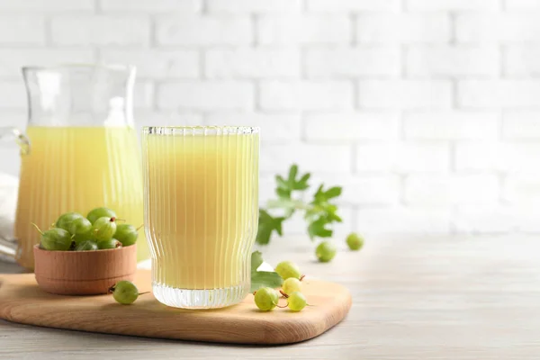 stock image Tasty gooseberry juice and fresh berries on light wooden table. Space for text