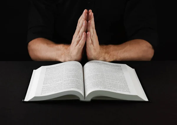 拿着圣经在黑桌祈祷的男人 特写镜头 — 图库照片