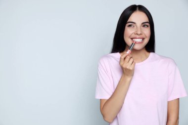 Gri arka planda çıplak ruj süren güzel genç bir kadın. Mesaj için boşluk.