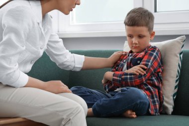 Psychologist working with unhappy little boy in office. Mental health problems