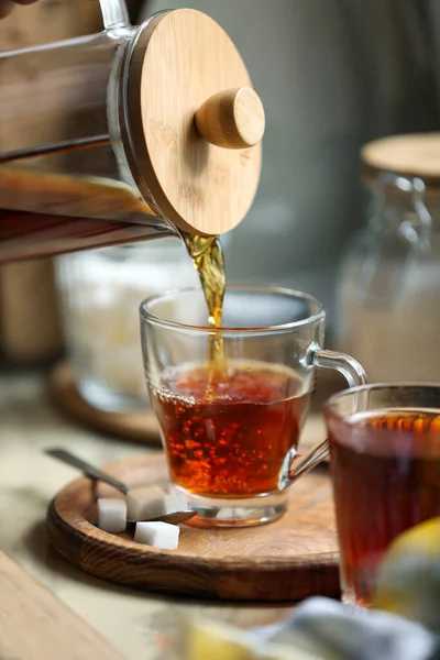 stock image Pouring delicious tea into glass cup on table, closeup