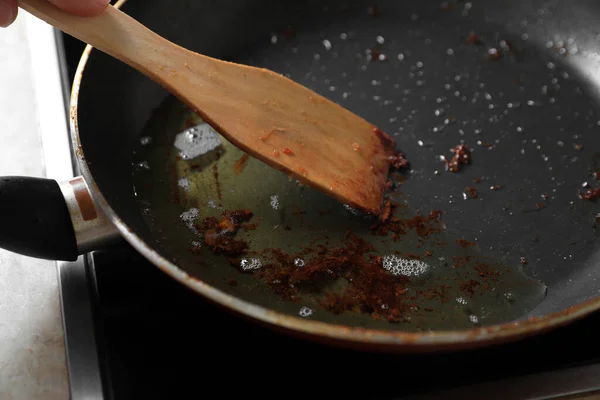 スパチュラでフライパンを揚げ ストーブの上で調理油を使用 クローズアップ — ストック写真