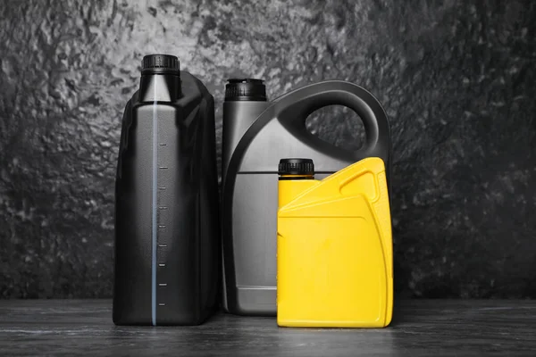 stock image Motor oil in different canisters on black table near dark wall