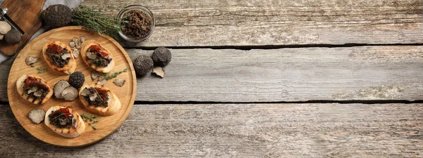 stock image Delicious bruschettas with truffle sauce and dried tomatoes on wooden table, flat lay with space for text. Banner design