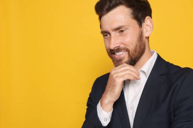 Takım elbiseli, gülümseyen sakallı adam turuncu arka plana bakıyor. Metin için boşluk
