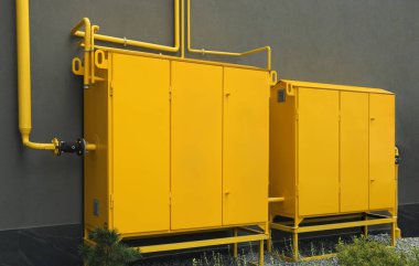 Kahverengi duvarın yanındaki sarı gaz dağıtım dolabı.
