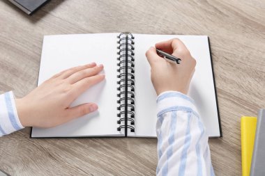 Ahşap masada deftere yazan kadın, yakın plan.