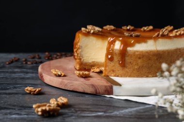Karamelli ve cevizli dilimlenmiş lezzetli cheesecake, siyah mermer masada, mesaj için yer var.