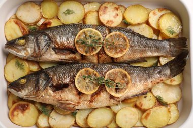 Lezzetli fırınlanmış deniz levreği ve patates tabağı, üst manzara.