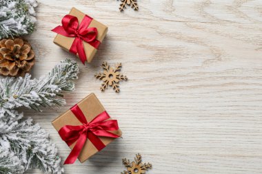 Hediye kutuları, köknar ağacı dalları ve beyaz ahşap masa üzerindeki Noel süsü, düz bir şekilde. Metin için boşluk