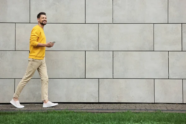 Homem Bonito Com Smartphone Andando Perto Parede Pedra Cinza Livre — Fotografia de Stock