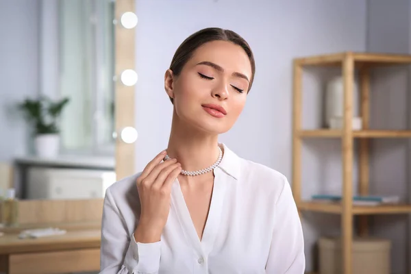 Mujer Joven Probándose Elegante Collar Perlas Interior — Foto de Stock