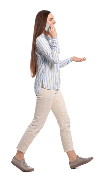 白地を背景に歩きながらスマホで話すカジュアルな服装の若い女性 — ストック写真
