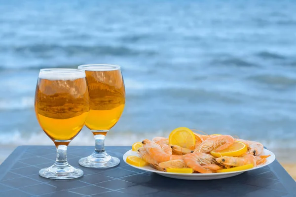 stock image Cold beer in glasses and shrimps served with lemon on beach