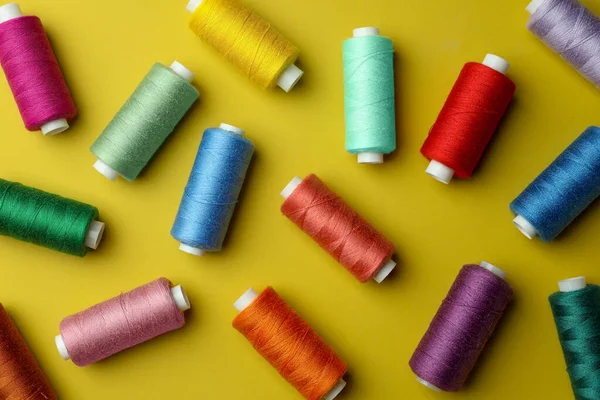 黄色の背景に異なるカラフルな縫製糸 フラットレイ — ストック写真